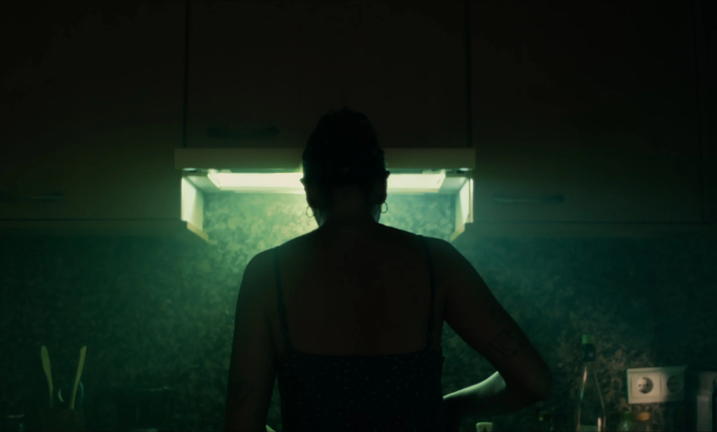 Persona de espaldas cocinando bajo una campana de cocina iluminada.