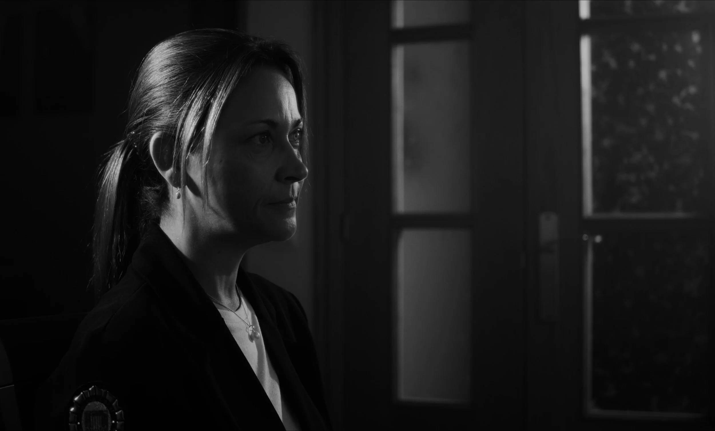 Retrato en blanco y negro de una mujer mirando hacia la izquierda, con luz dramática y fondo oscuro.