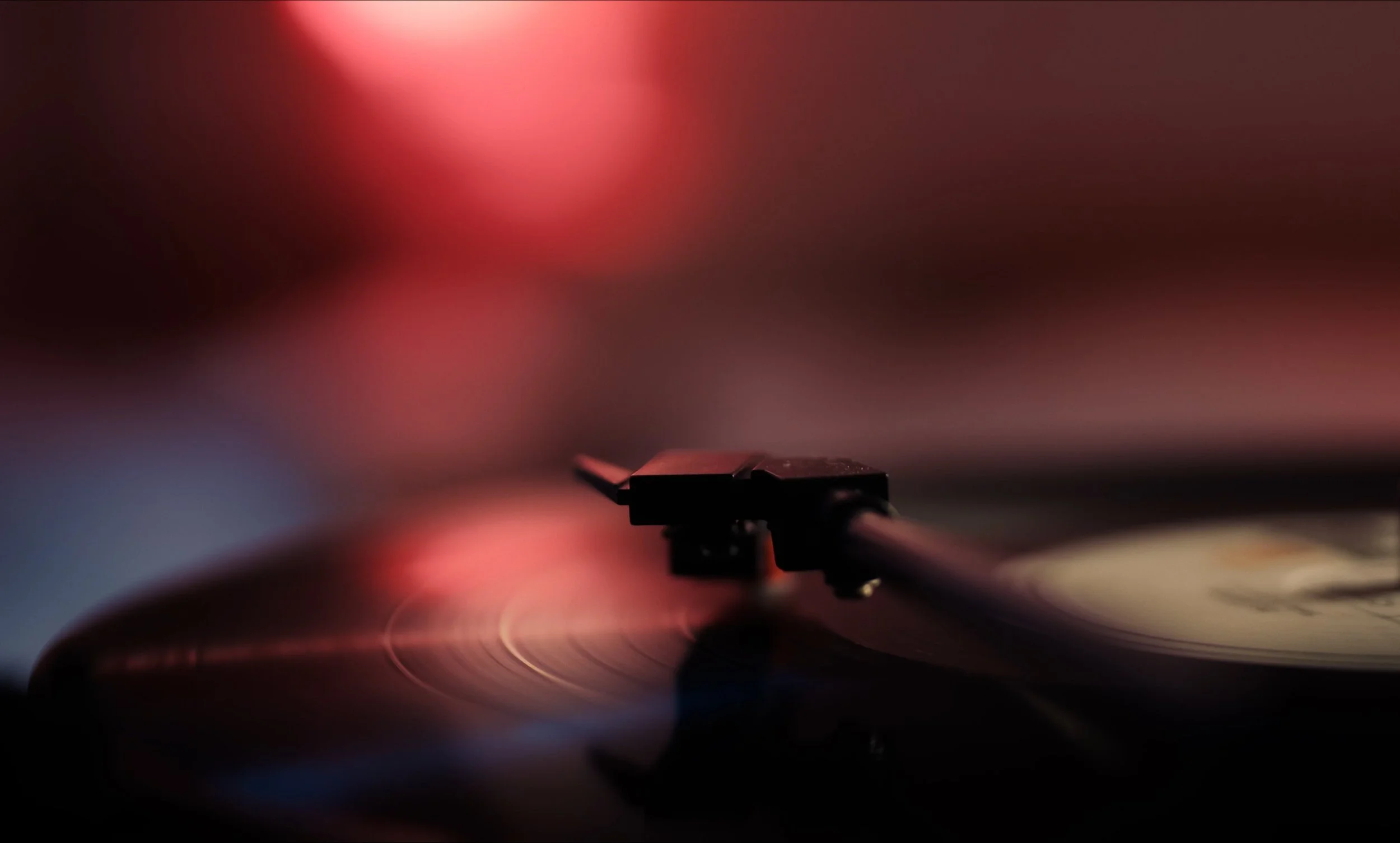 Tocadiscos y aguja reproduciendo un vinilo con fondo desenfocado.