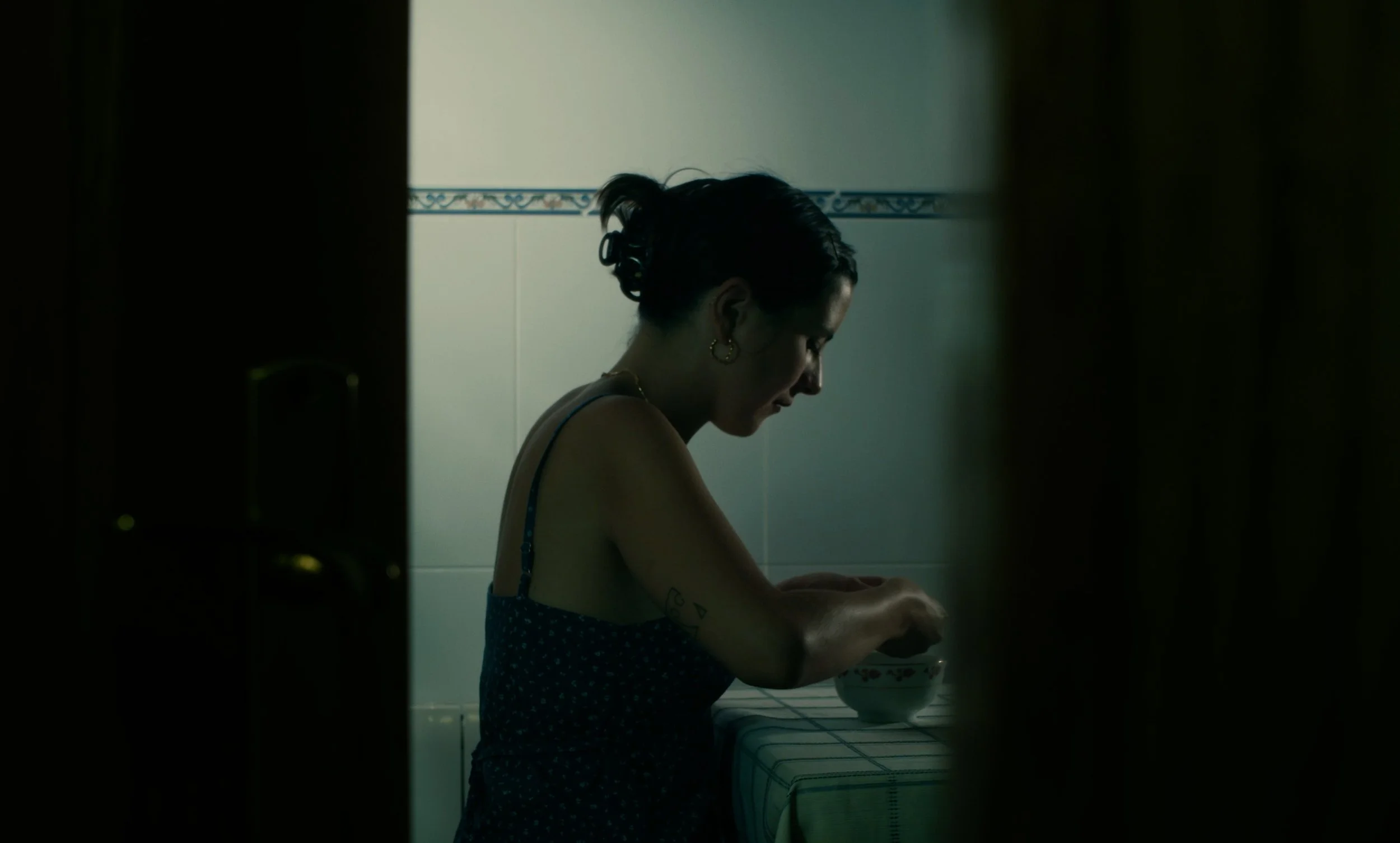 Mujer de perfil sentada a una mesa interior con un bol.