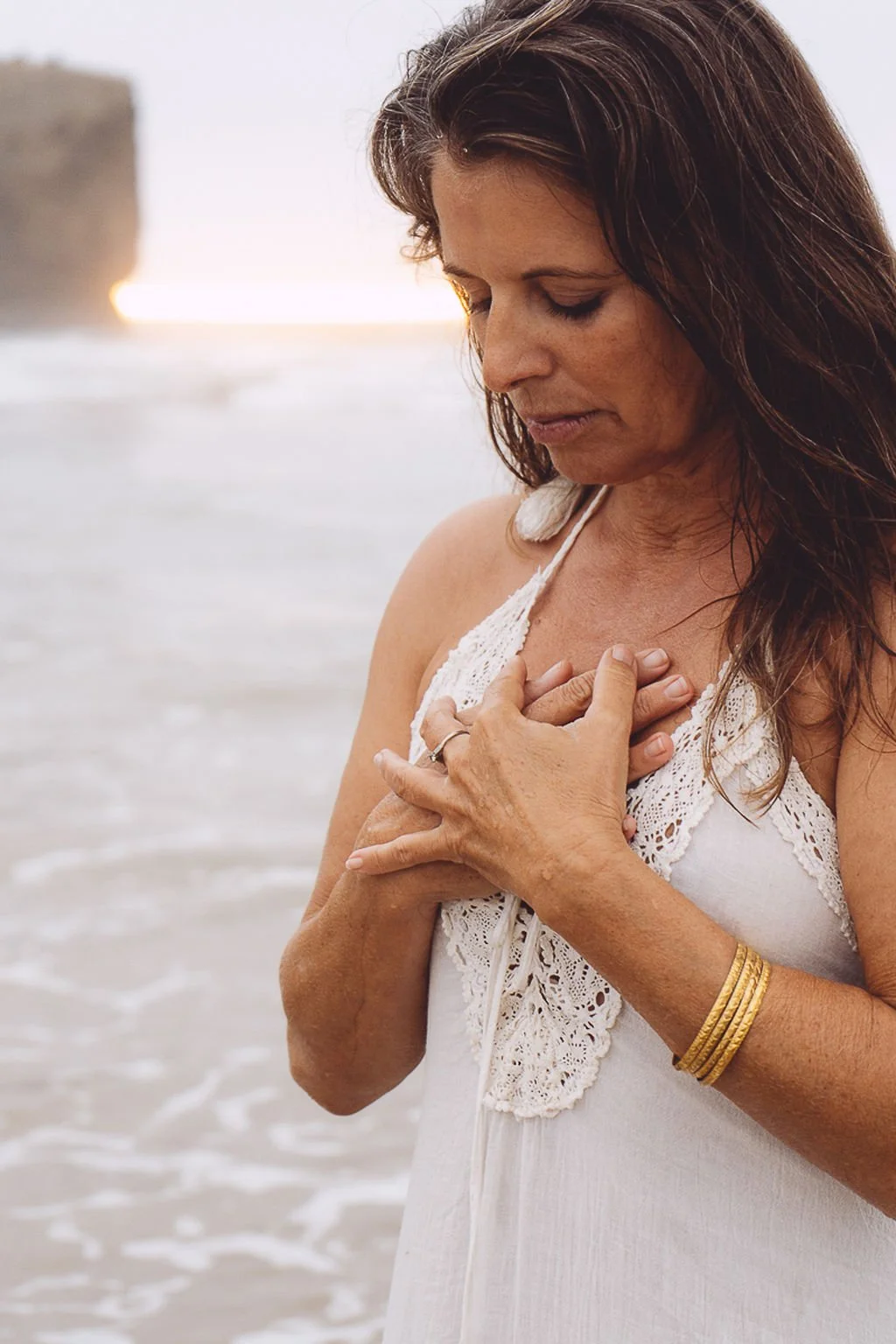 women in white dress and two hands  with golden arm rings, on her heart