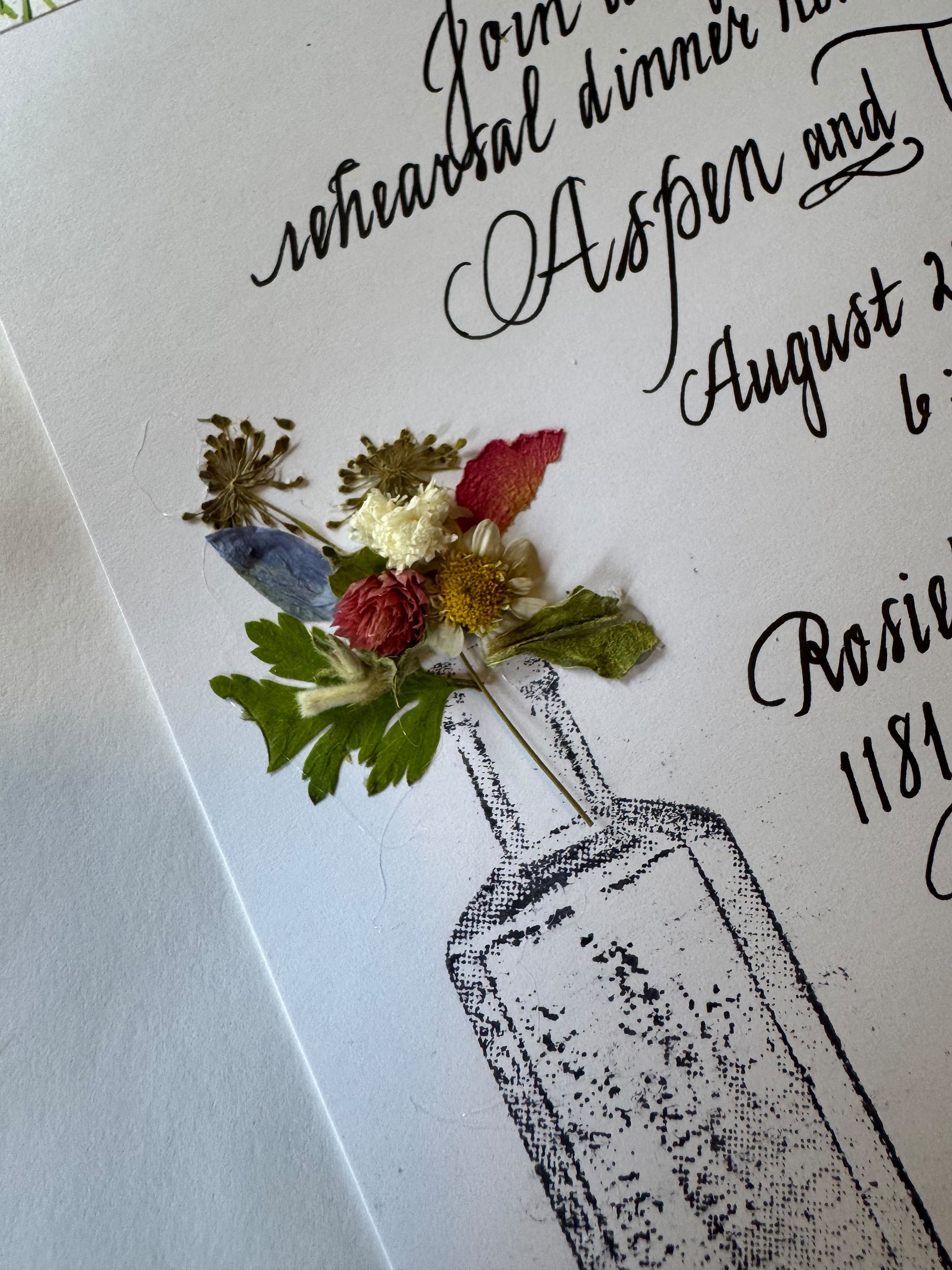 Close-up of a handwritten note with decorative dried flowers attached.