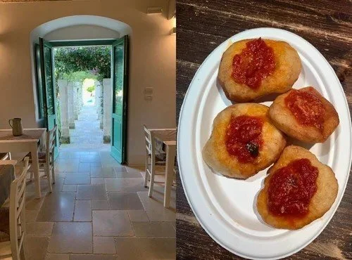 View of an open door leading outside with a stone pathway, and a plate of four fried snacks topped with red sauce on a wooden table.