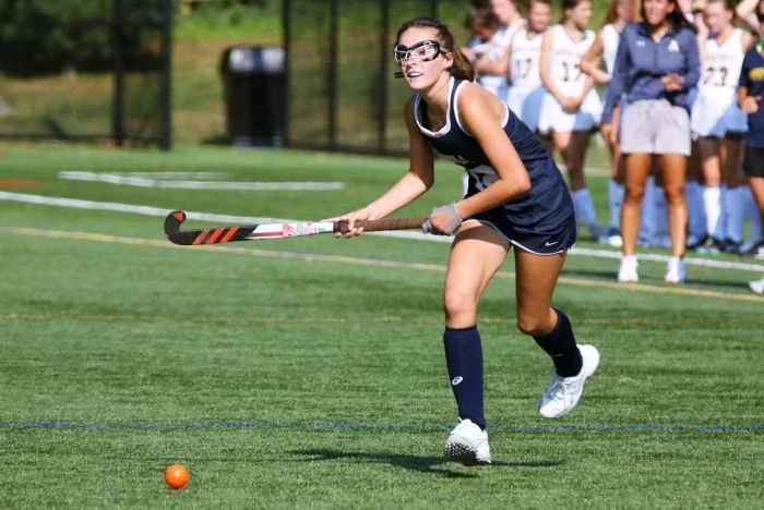 A teen girl playing field hockey on game day.