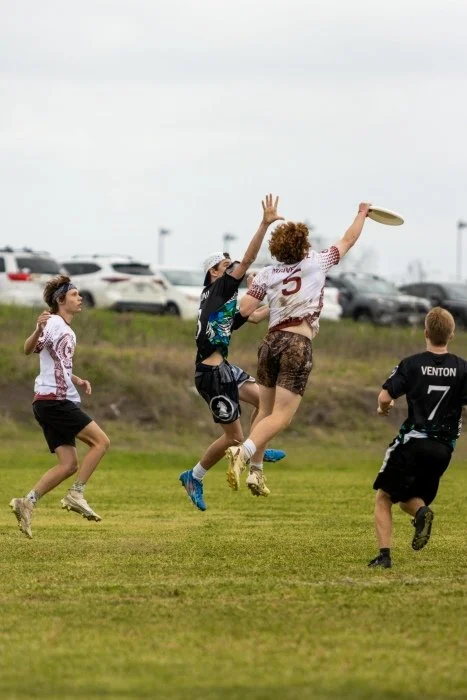 A group of boys playing ultimate frisbee outside.
