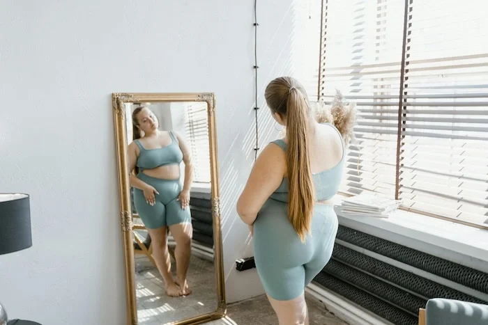 Woman in athletic clothes looking into a mirror.