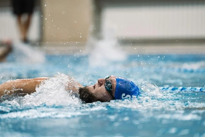 A man swimming laps in an indoor pool.