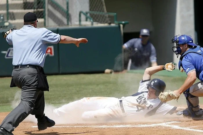 Guy sliding home and being called safe in a baseball game.