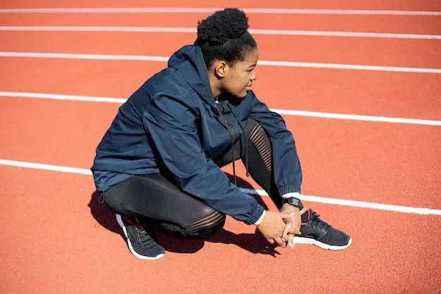A woman crouching down on track contemplating her next move.