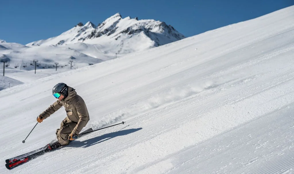 image of ski instructor carving turn with blue sky and mountains in background
