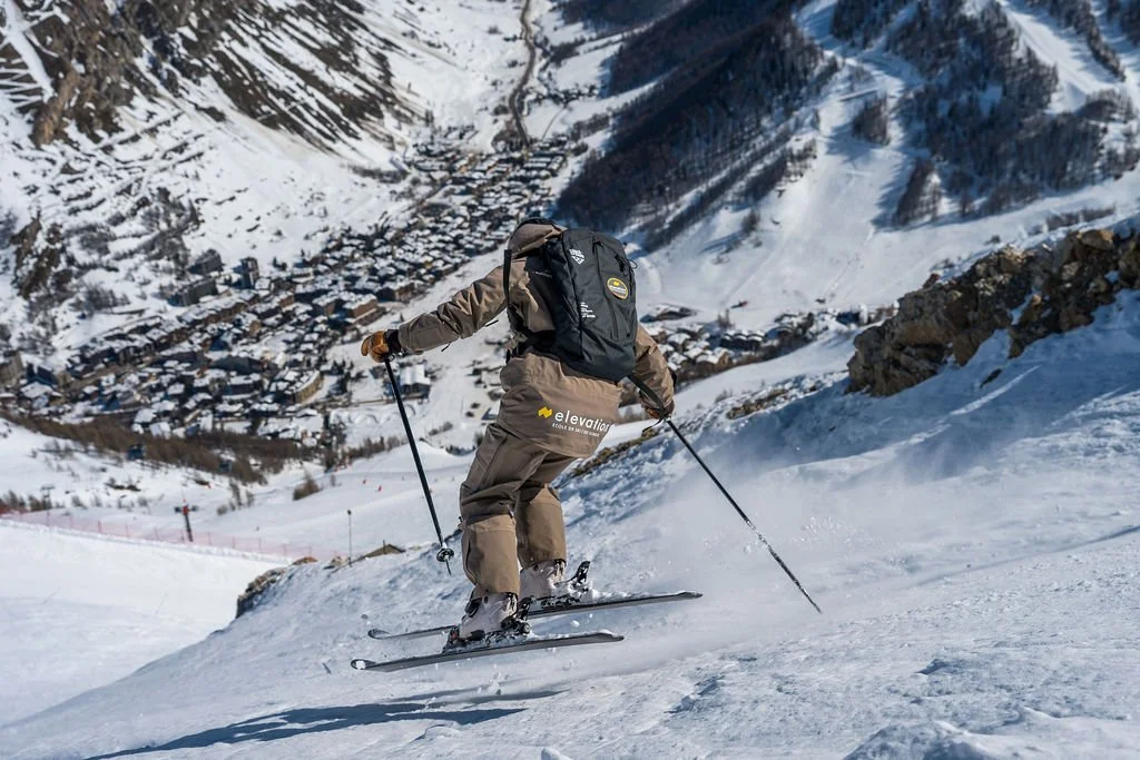 image shows Elevation ski instructor Simon McCombe skiing down slope with the ski resort of Val d'Isère in the valley below