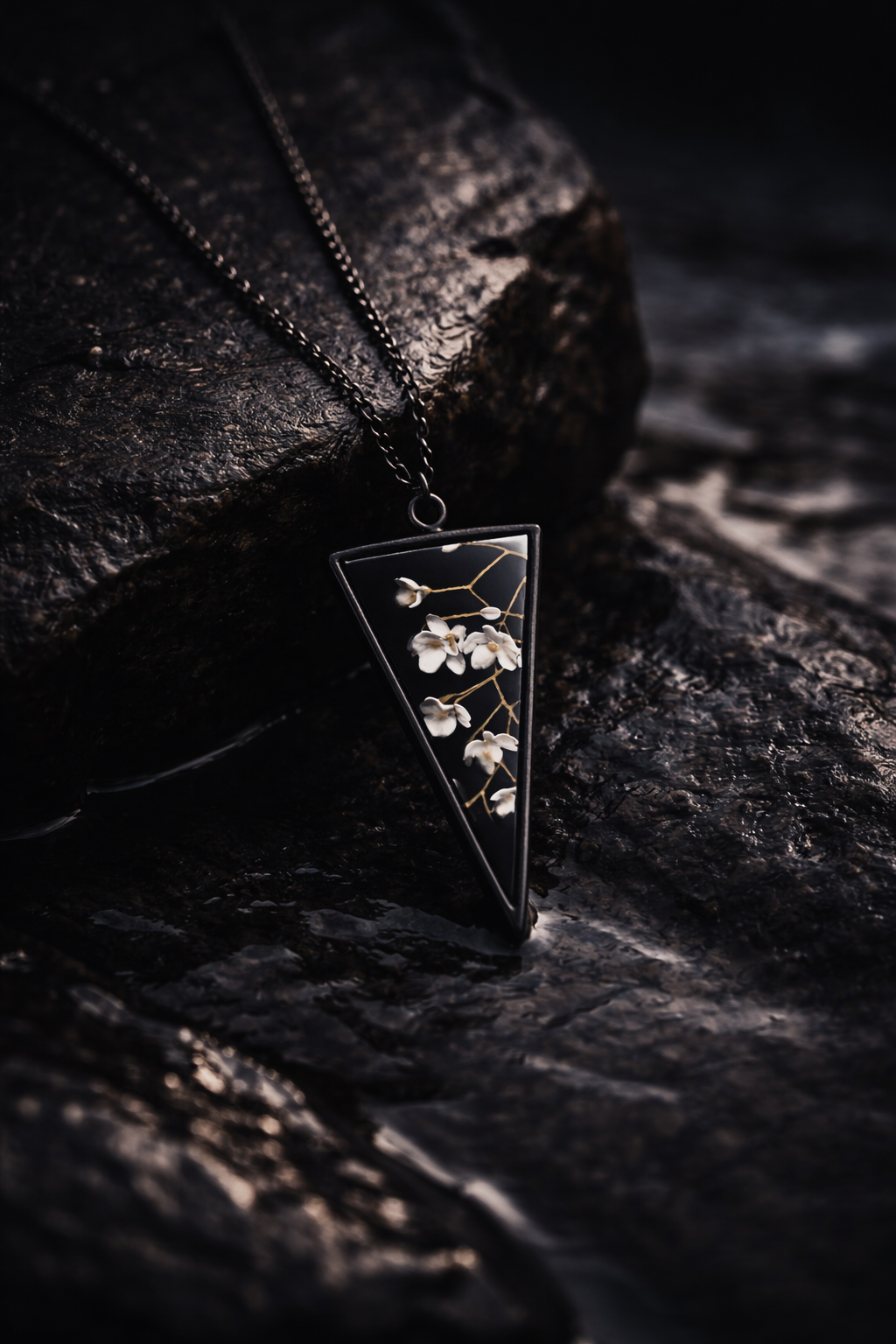 floral pendant set against black sand beach with ocean backdrop