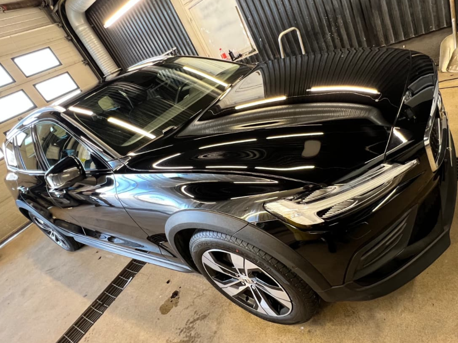 Svart bil i en garage, reflekterande ljus på ytan, modern design med stora hjul.