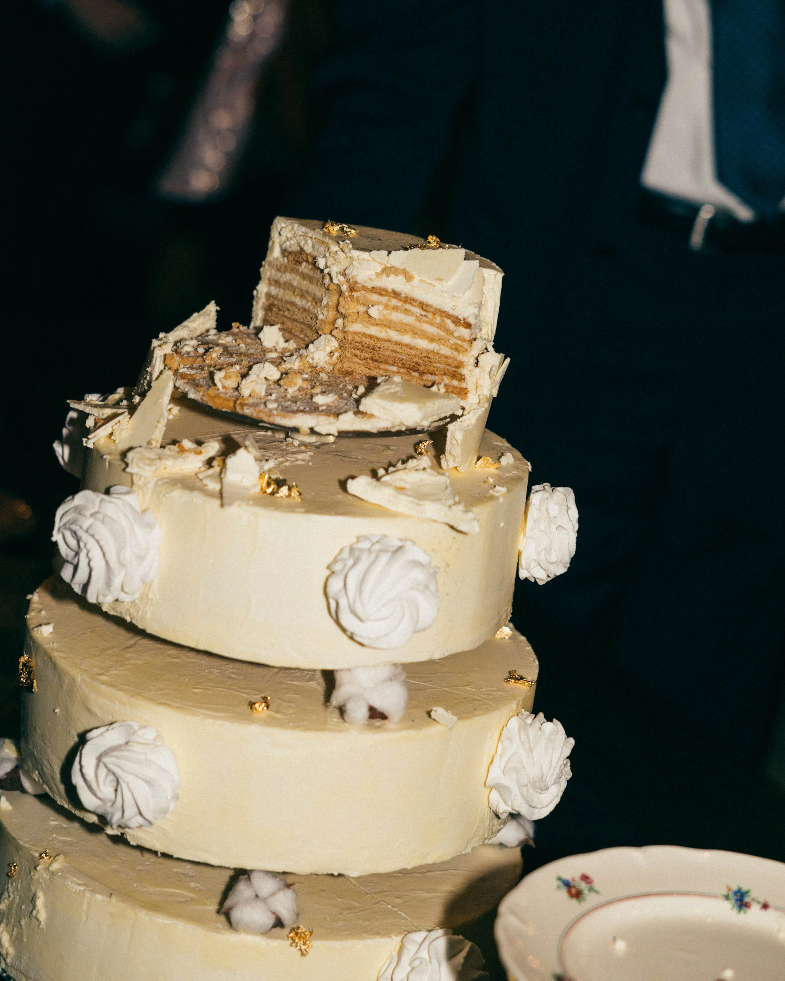 Gâteau de mariage à plusieurs niveaux, décoré de meringues blanches, avec une tranche de gâteau montrant des couches de biscuit et de crème, sur le dessus.