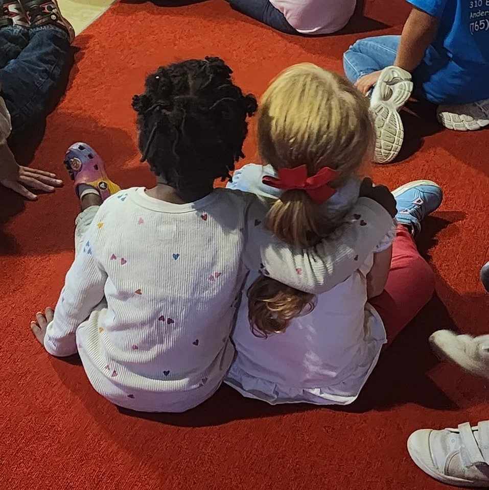 People from different races and backgrounds put their hands in the middle of a circle.