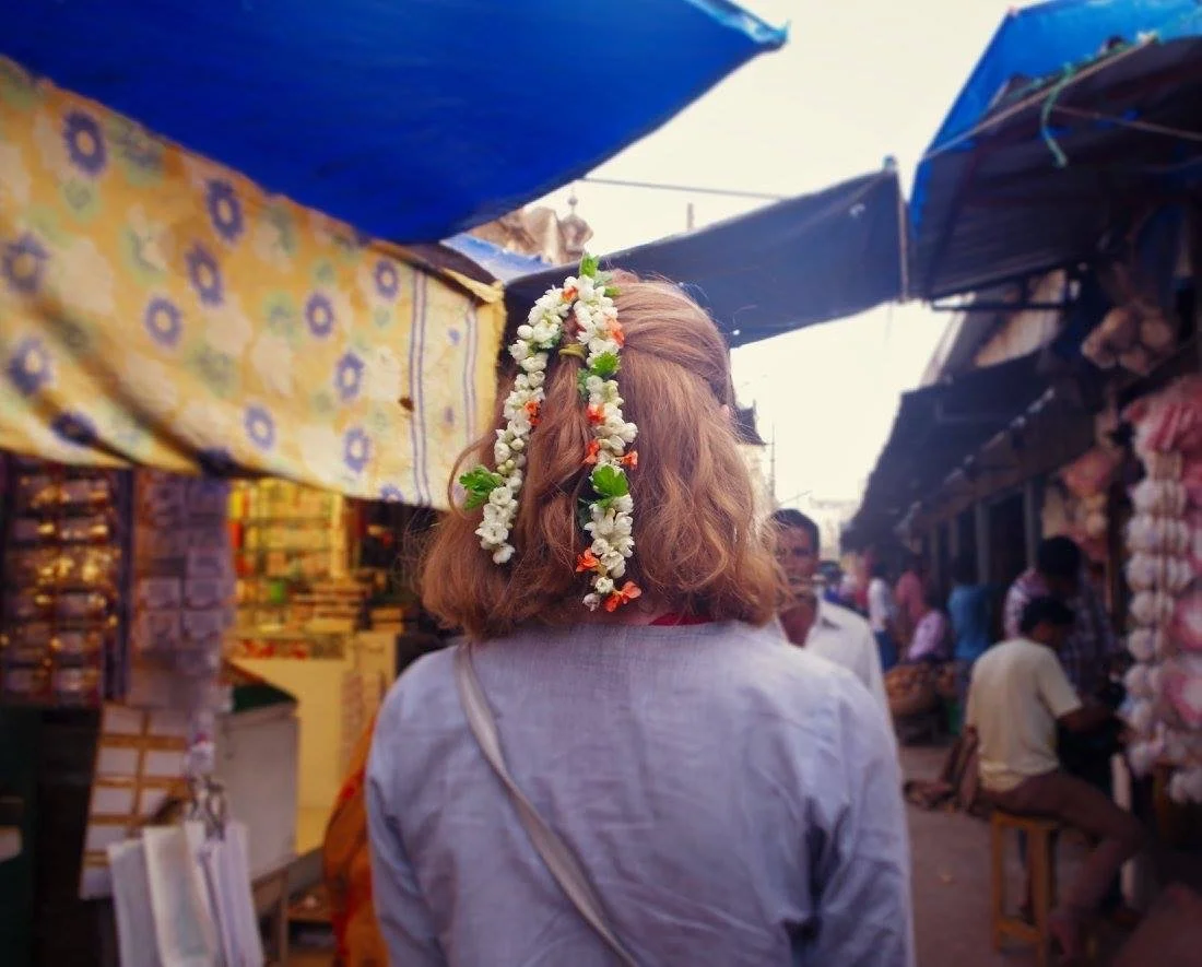 Woman with flowers in her hair exploring a local market while traveling through India