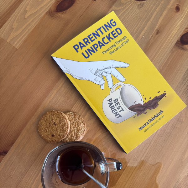 Copy of Parenting Unpacked: Parenting Through the Loss of Self by author Jessica Gabrielzyk paired with coffee and cookies on a wooden desk.