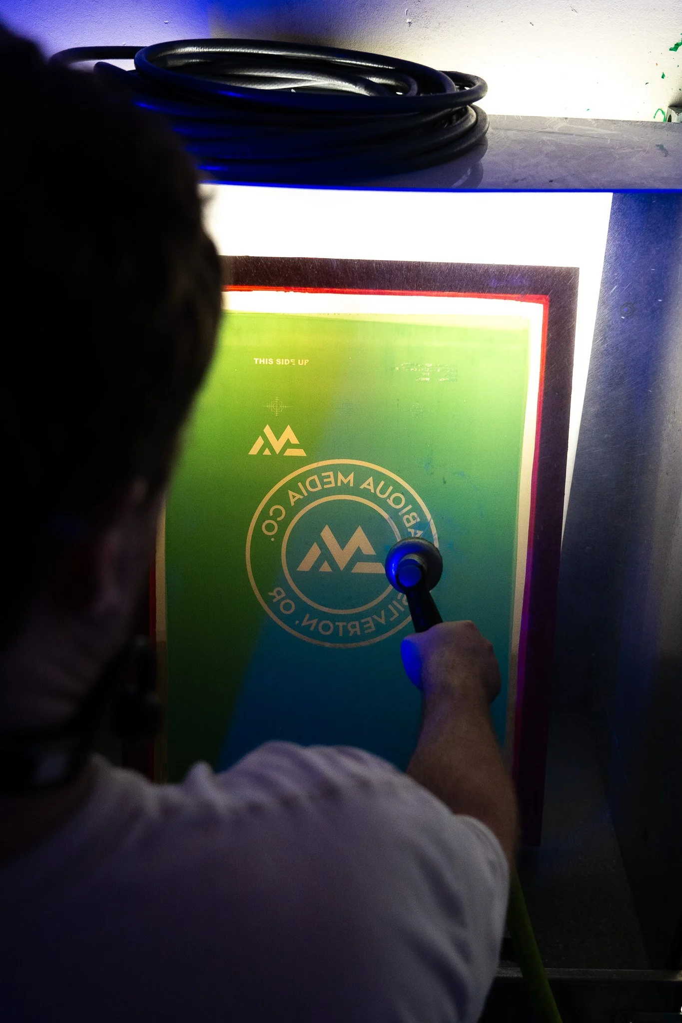 A business logo is being pressure washed out of the silk screen, revealing a stencil.