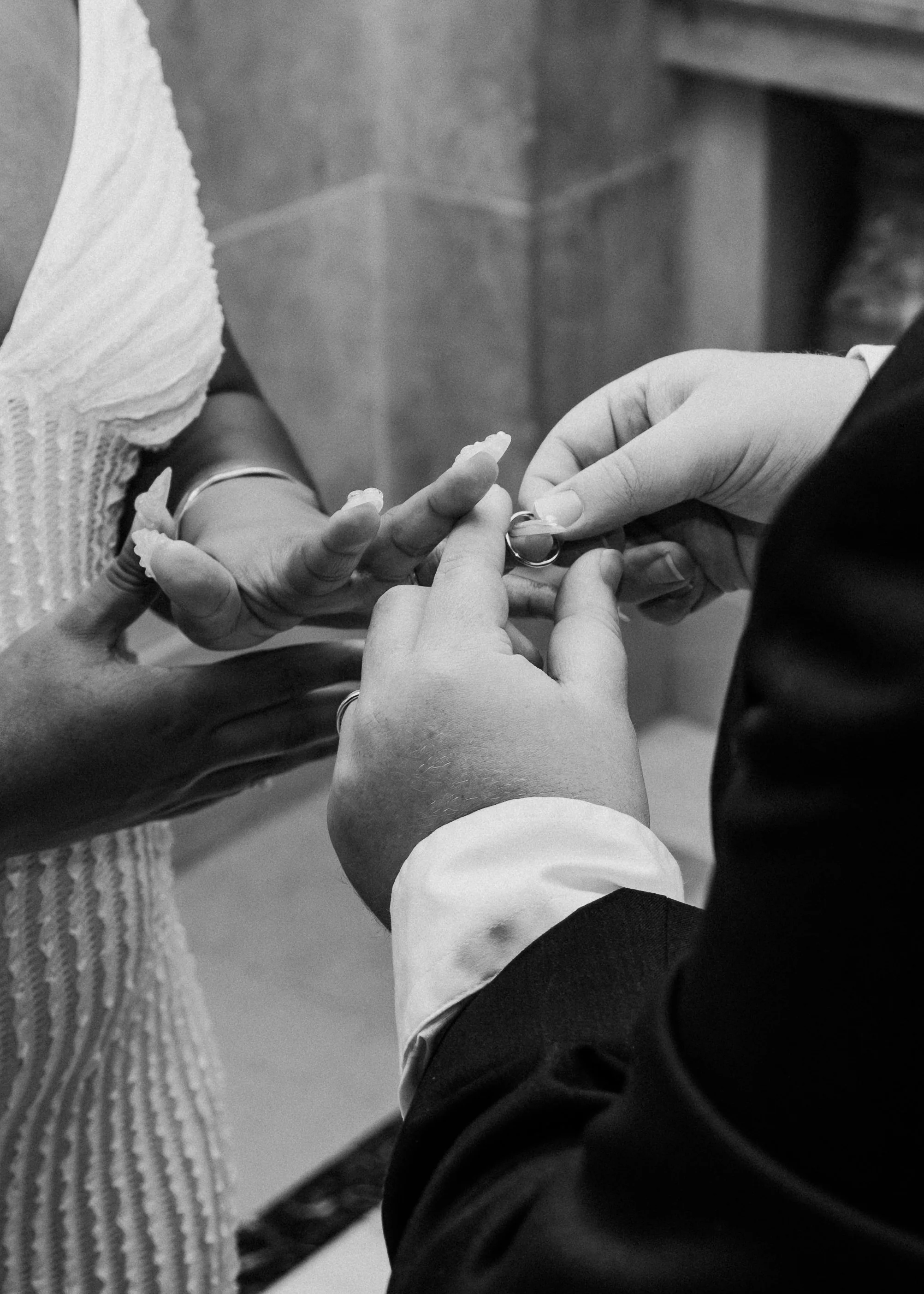A wedding ceremony where a person is placing a wedding ring on their partner's finger.