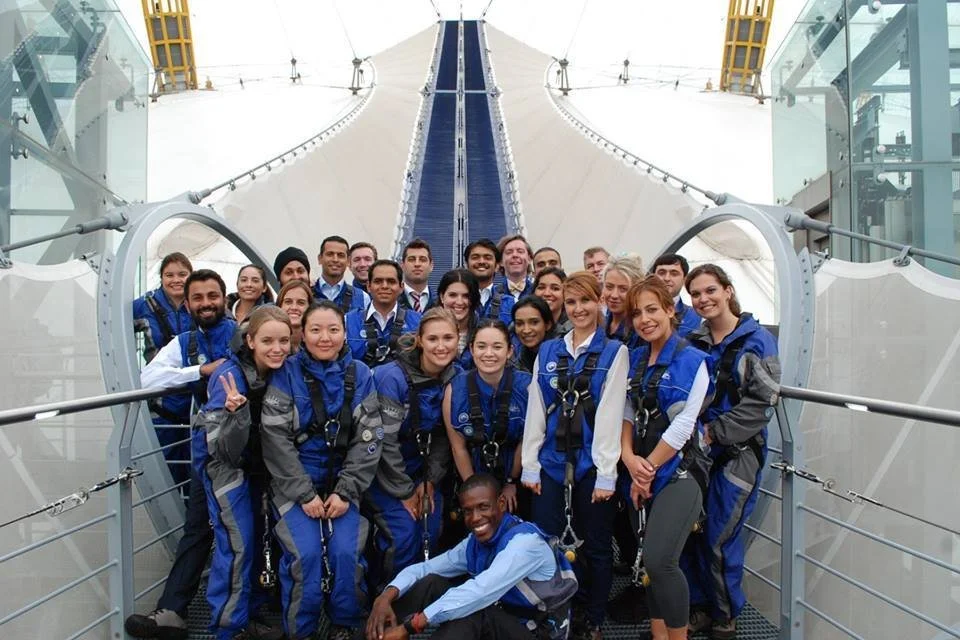 Group of people in blue and gray uniforms standing inside a spacecraft or space training facility.