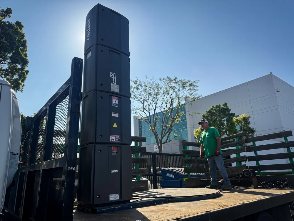Forklift loading large equipment beside a Sustainable Cleanouts truck