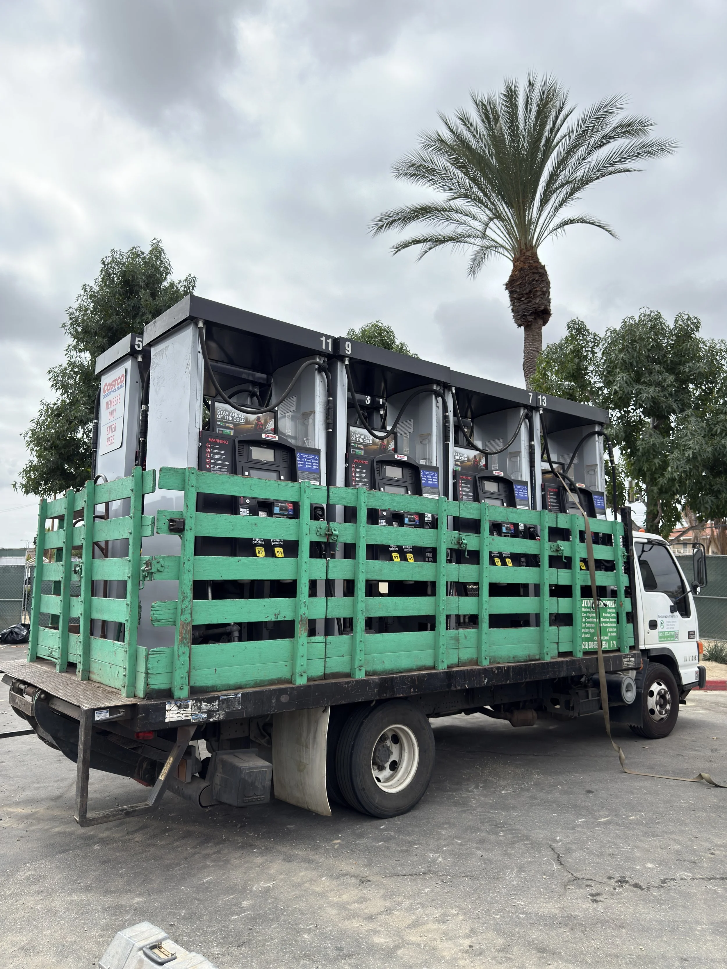 Sustainable Cleanouts truck with green side rails and a black roll-off container at a commercial property.