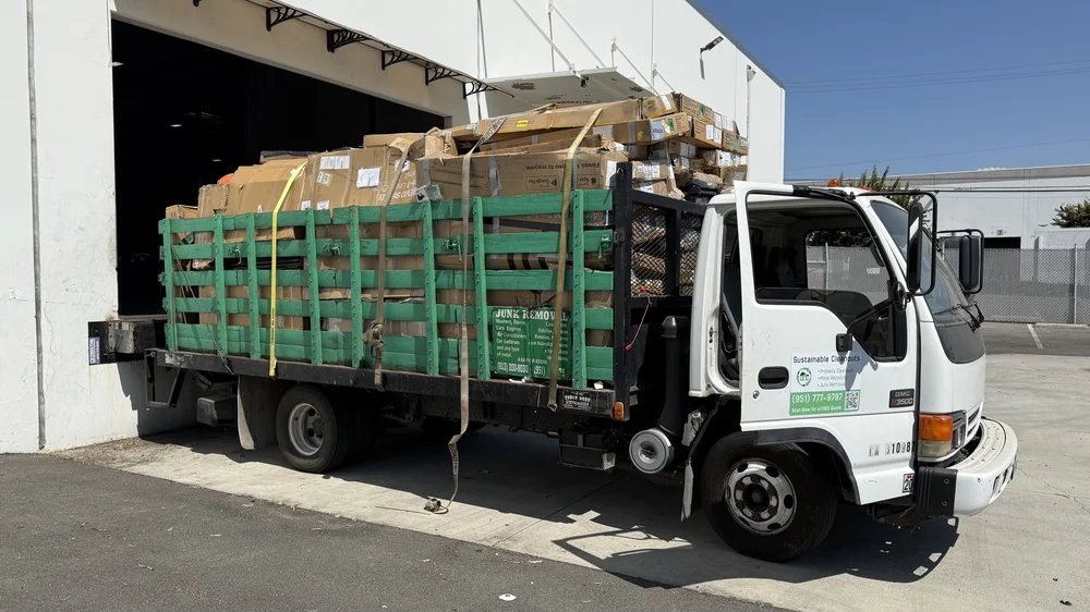Loaded Sustainable Cleanouts stakebed truck outside a commercial loading bay