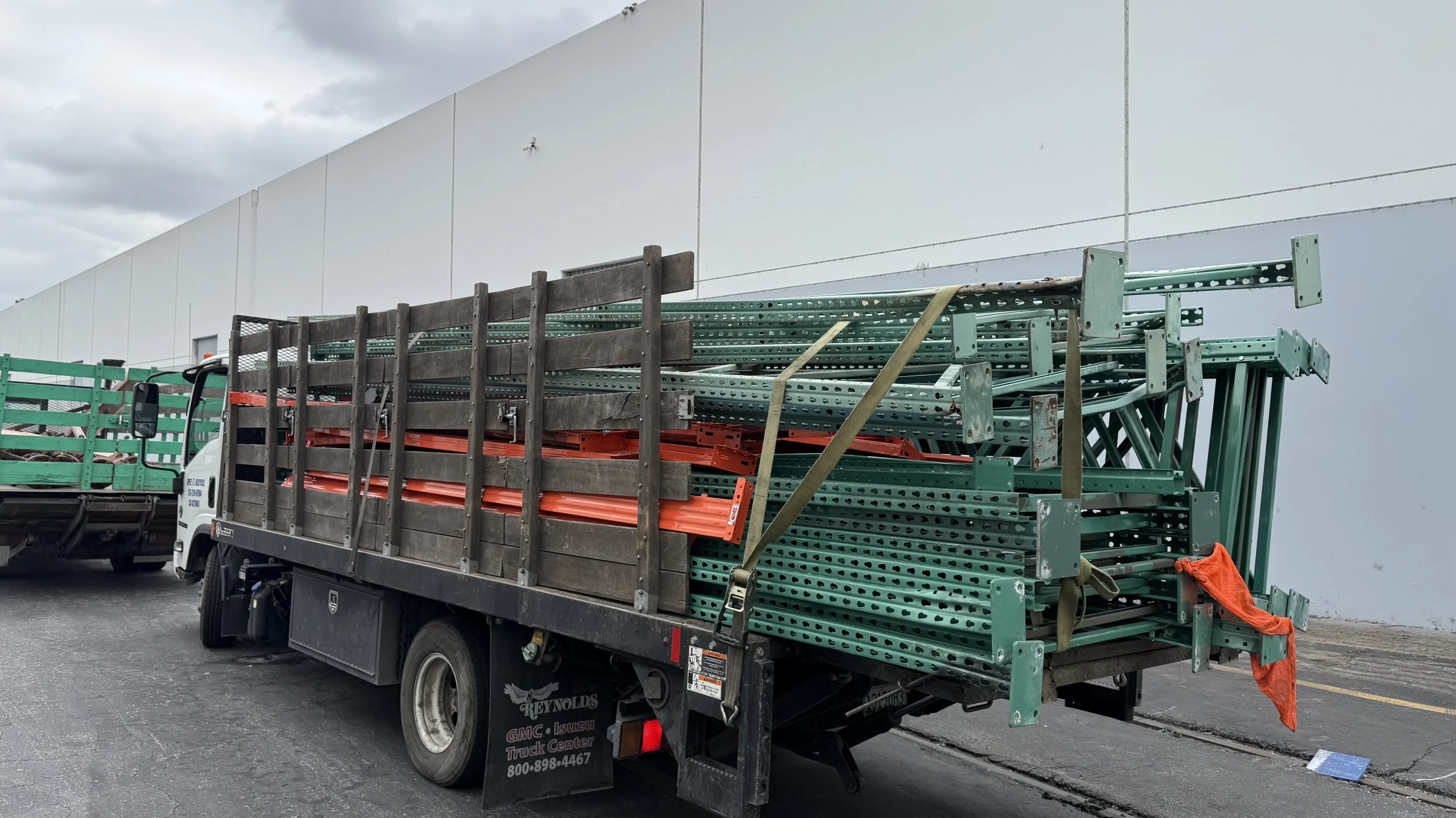 Sustainable Cleanouts truck carrying green commercial racks outside a warehouse.