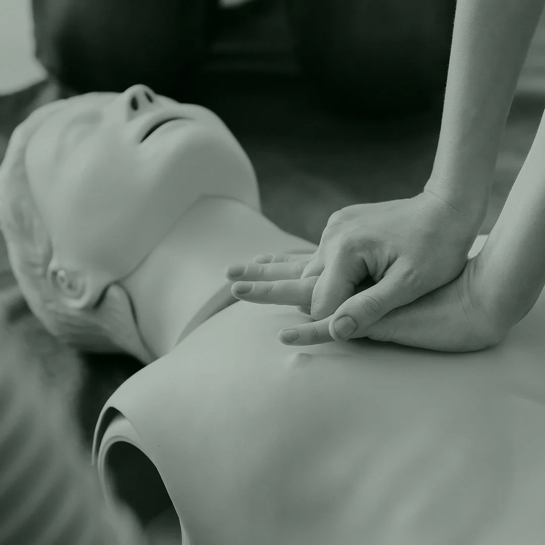 A person performing CPR on a mannequin during a training session.