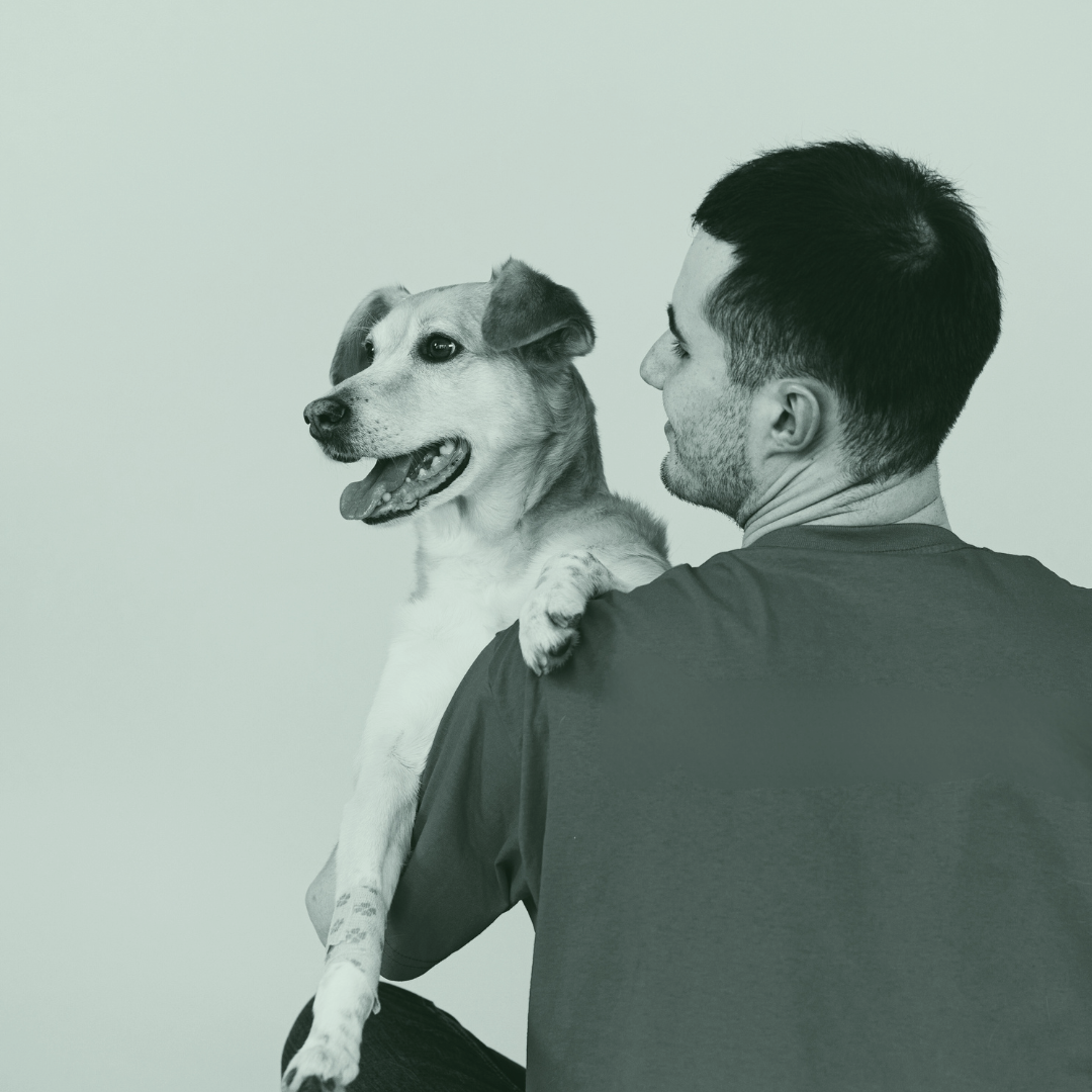 A man holding a happy dog with one paw on his shoulder, both facing to the left.