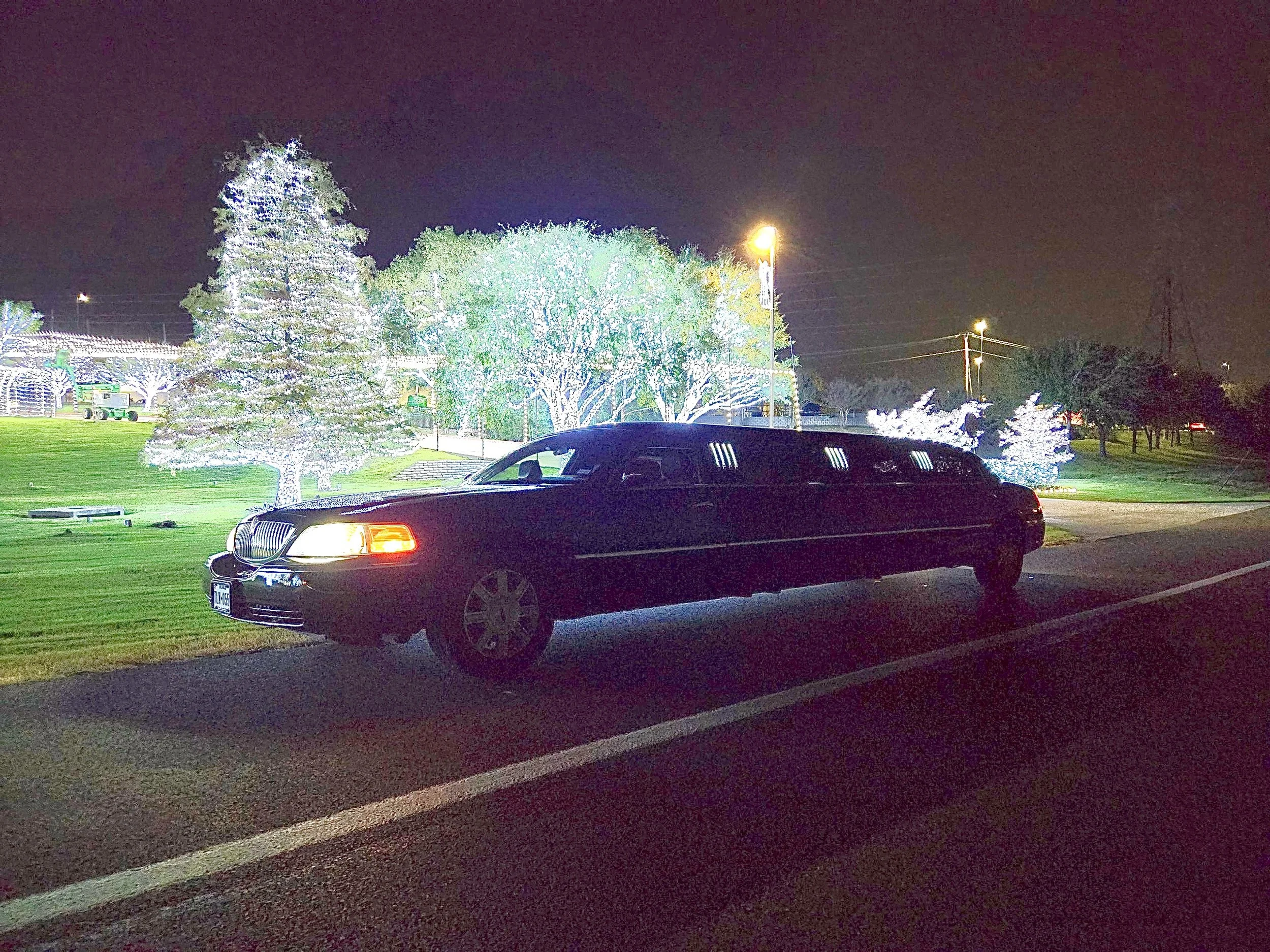 A Lincoln stretch limousine parked in front of the holiday lights at daystar