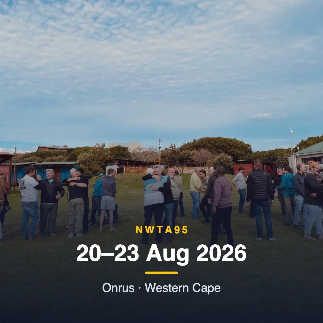 Group of people gathering outdoors on a grassy area in Western Cape, Onrus, during daytime, with some people hugging near a few small buildings, under a partly cloudy sky.