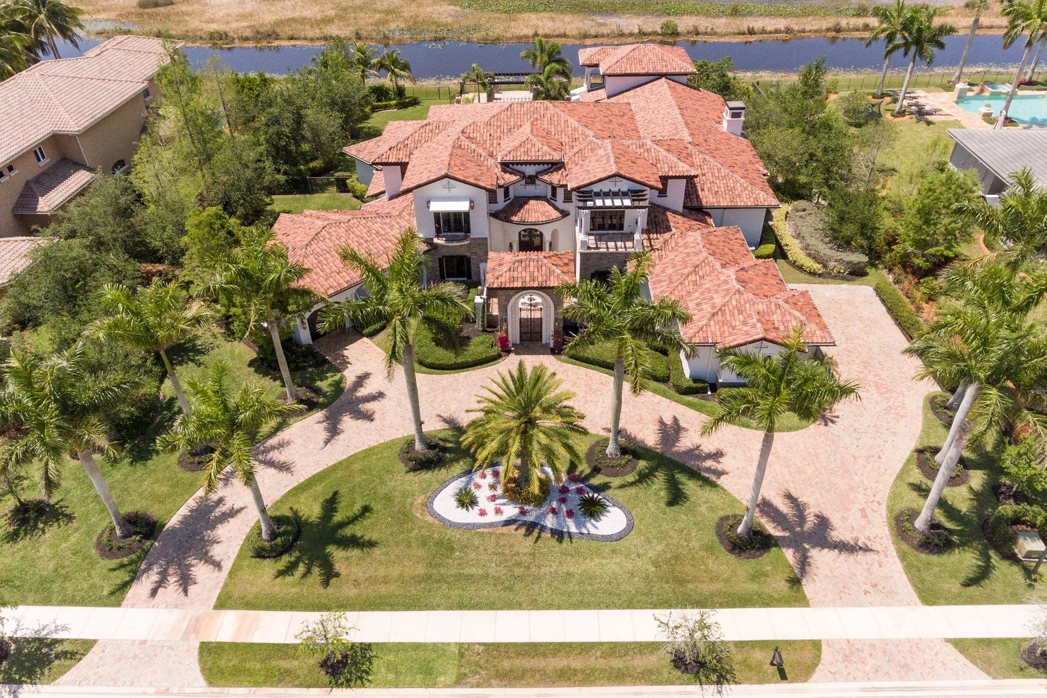 Aerial drone photograph of a luxury Mediterranean-style estate surrounded by palm trees, showcasing professional real estate photography in South Florida.