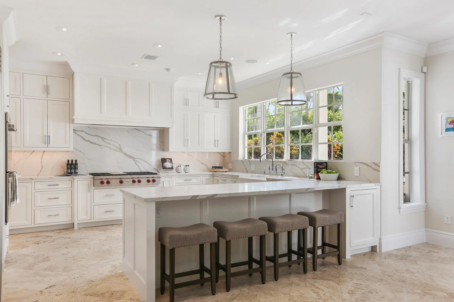 Bright luxury kitchen with white cabinetry, marble countertops and large island in a Pinecrest, Florida home.