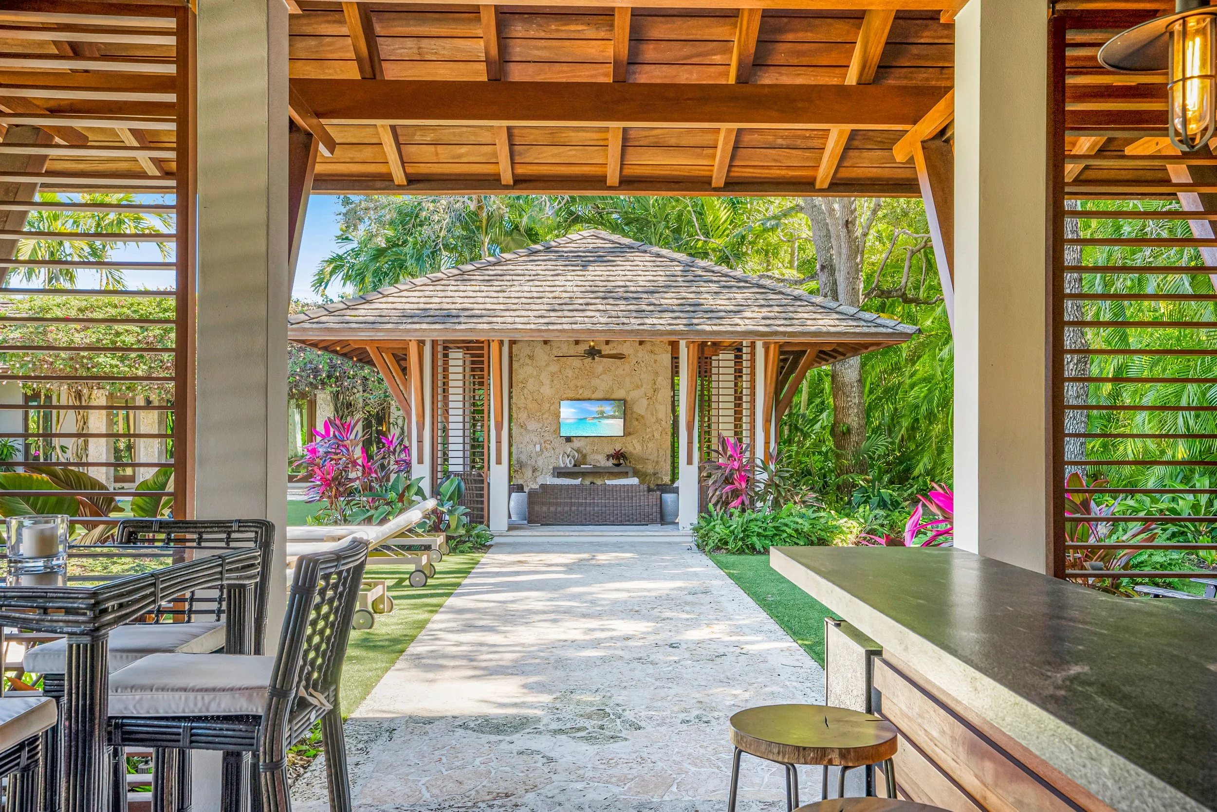 Covered outdoor living area with tropical landscaping and gazebo at a luxury home in Pinecrest, Florida.