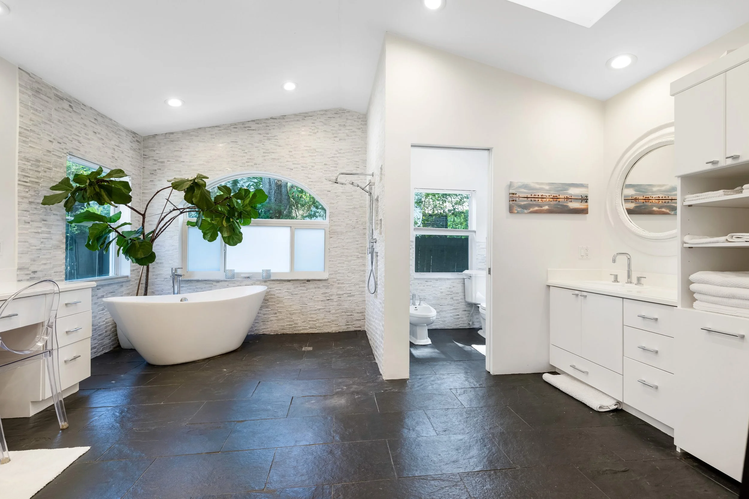 South Miami luxury home primary bathroom with freestanding soaking tub, modern vanity and contemporary tilework.
