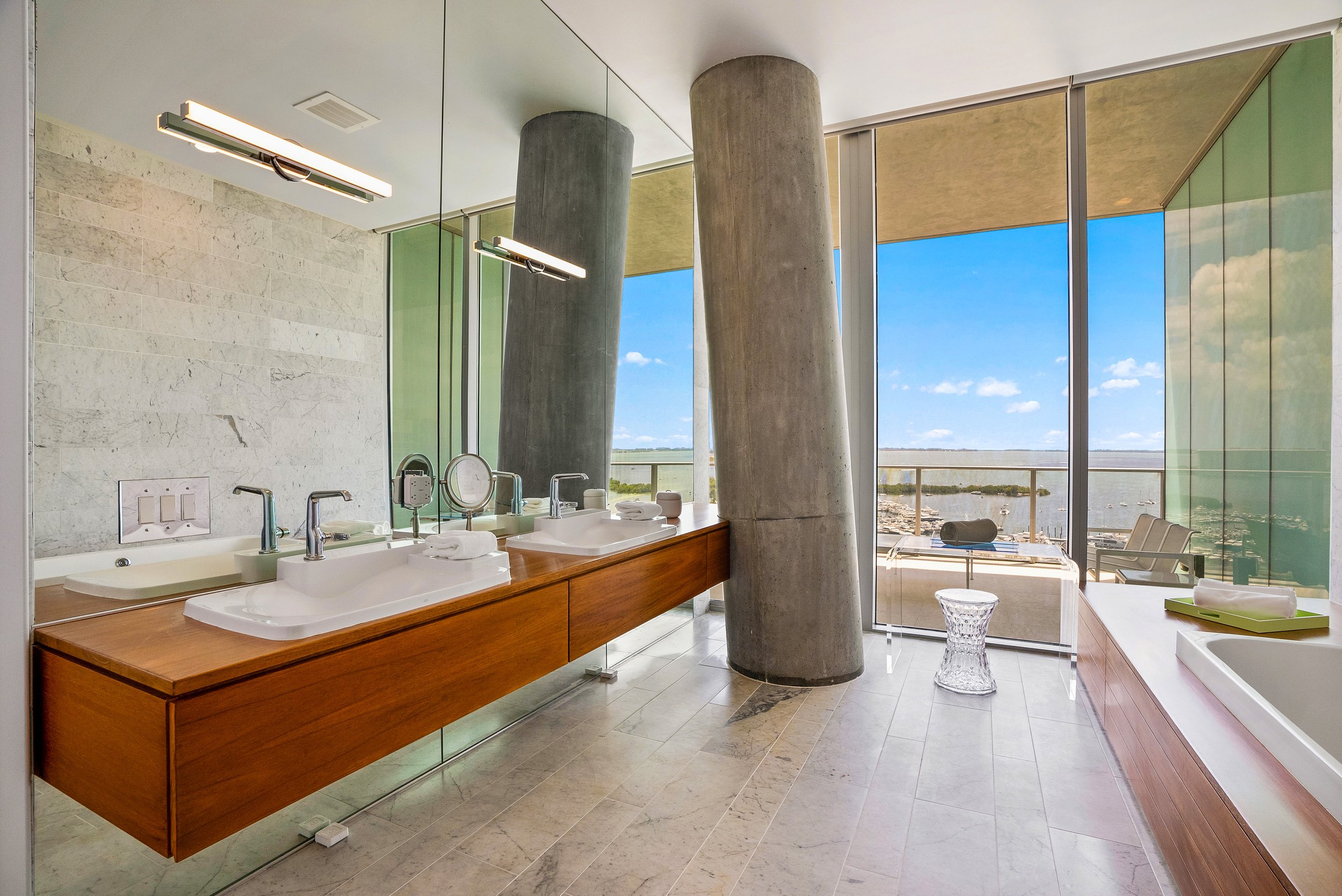 Luxury Coconut Grove condo bathroom with double vanity, floor-to-ceiling windows and Biscayne Bay views.
