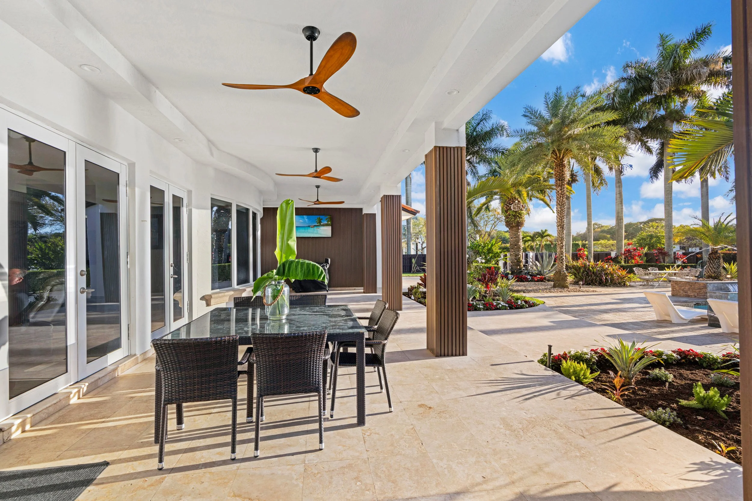 Covered outdoor living and dining area with tropical landscaping at a Homestead and Redland home.