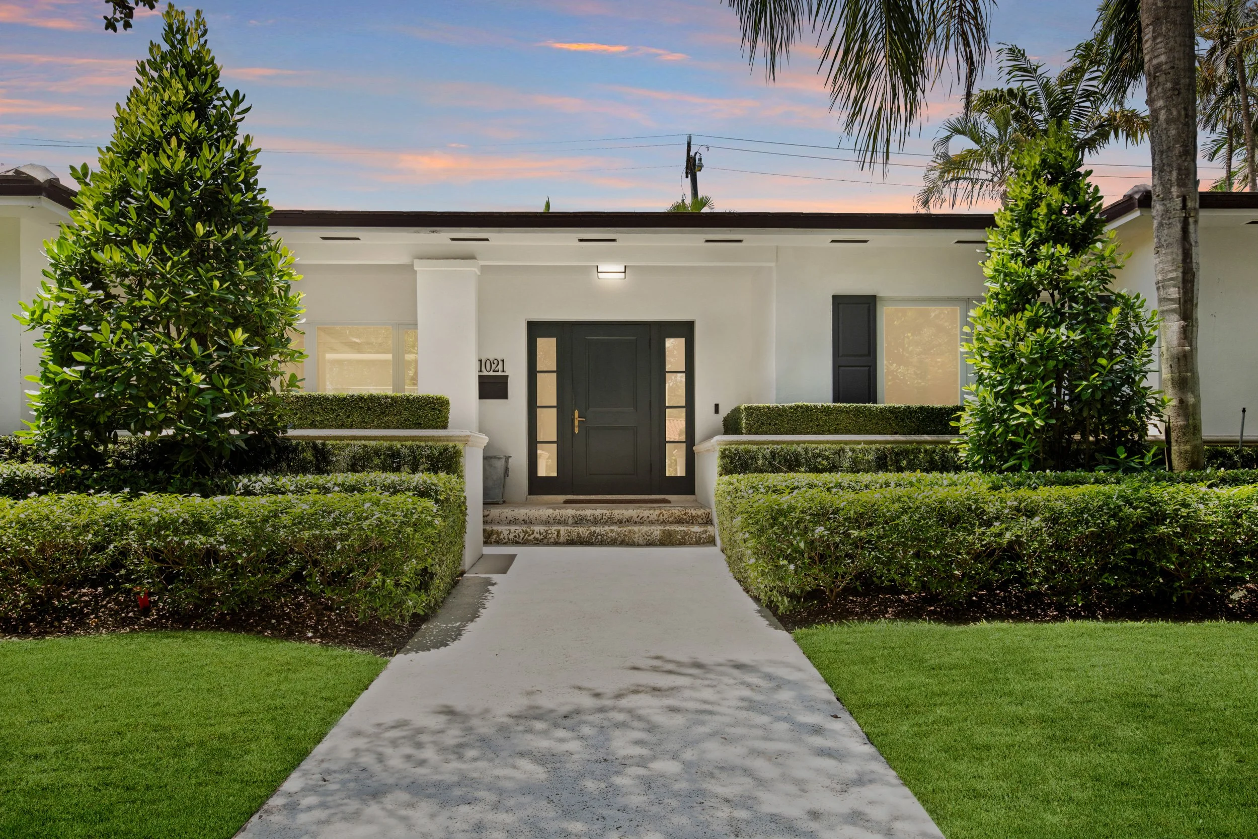 Coral Gables luxury home exterior with tropical landscaping photographed at twilight.