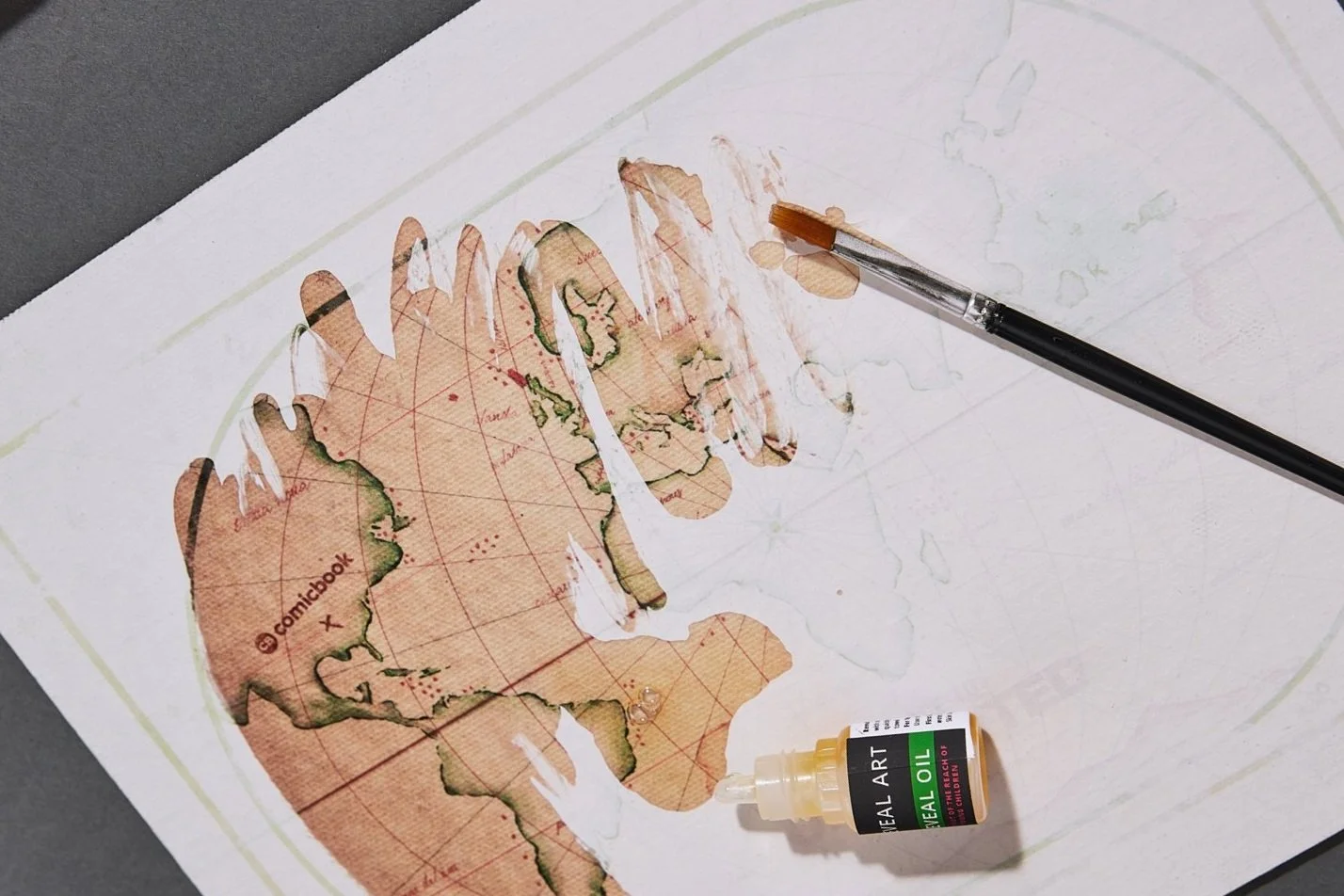 A vintage world map with a water dropper and a bottle of sealing oil on top.