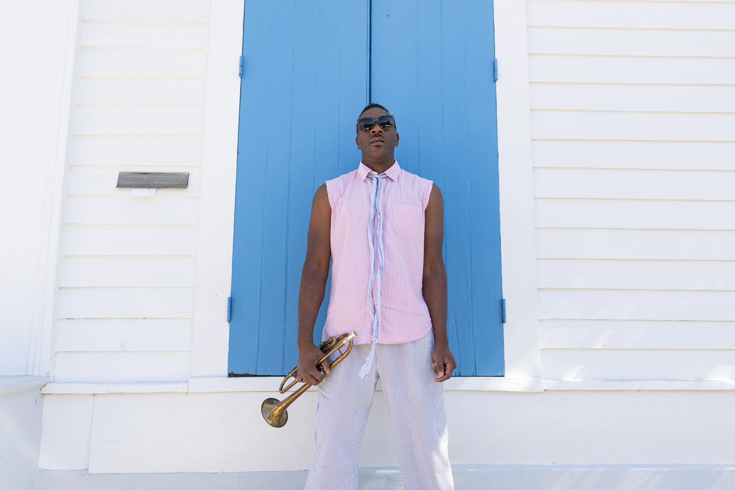 Troy Sawyer standing with his trumpet beside a blue doorway. Photo: Karl Ault.