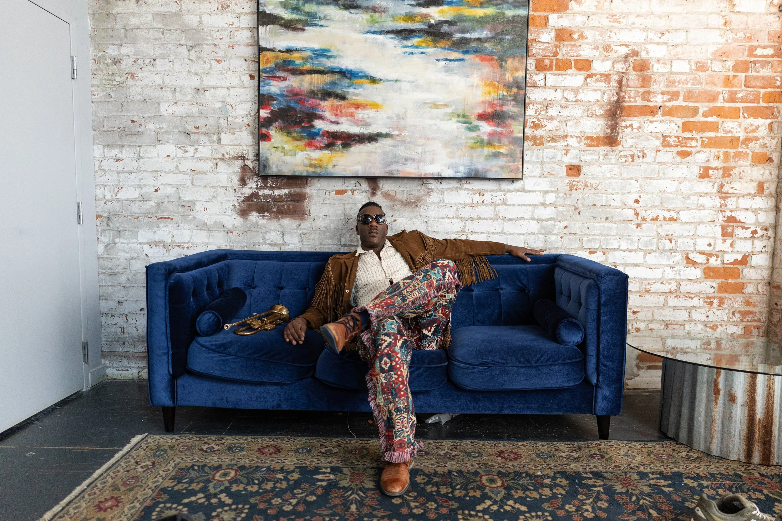 Troy Sawyer seated on a sofa holding his trumpet. Photo: Karl Ault.