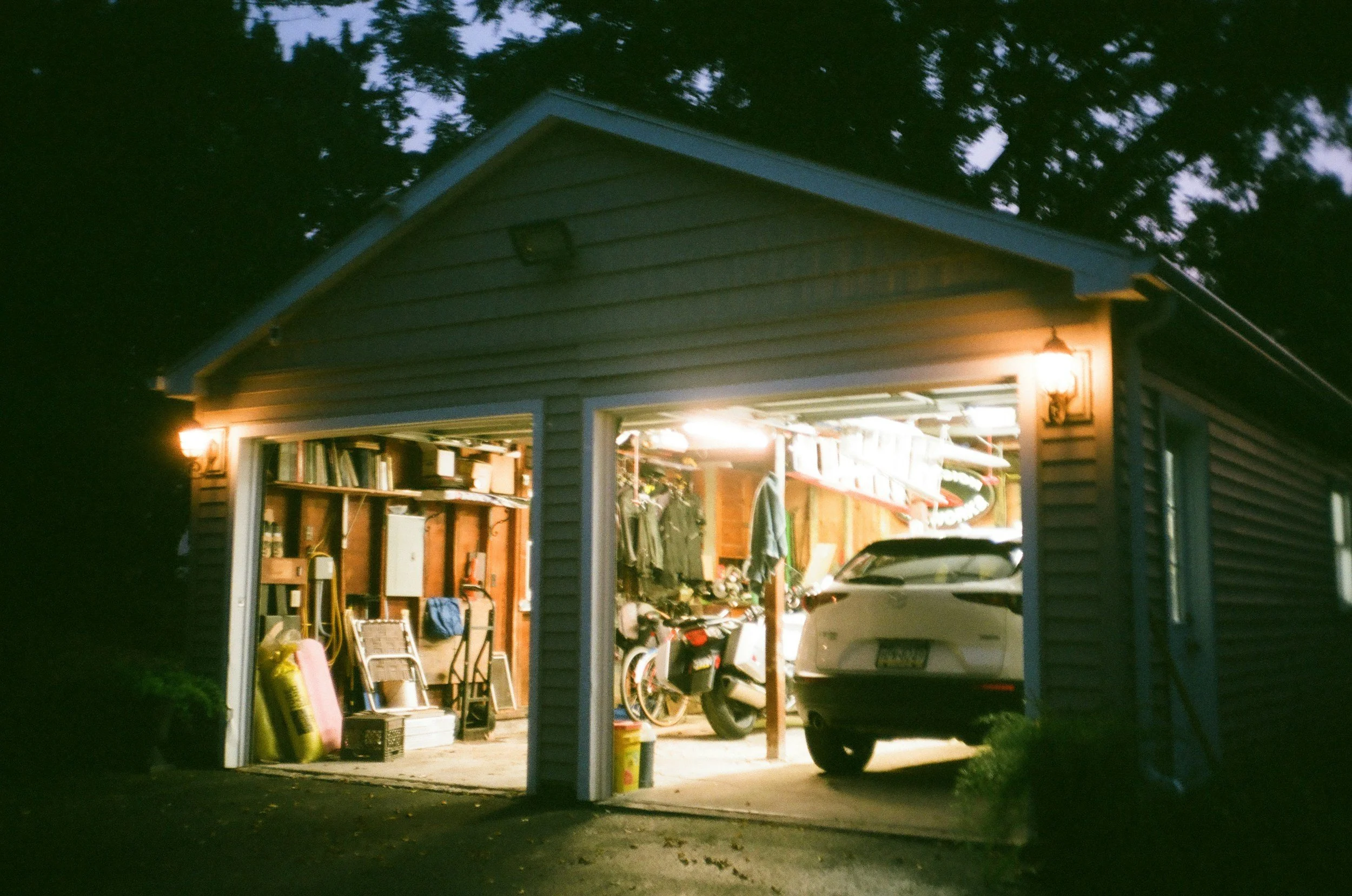 A full garage with lights on and an SUV parked in side