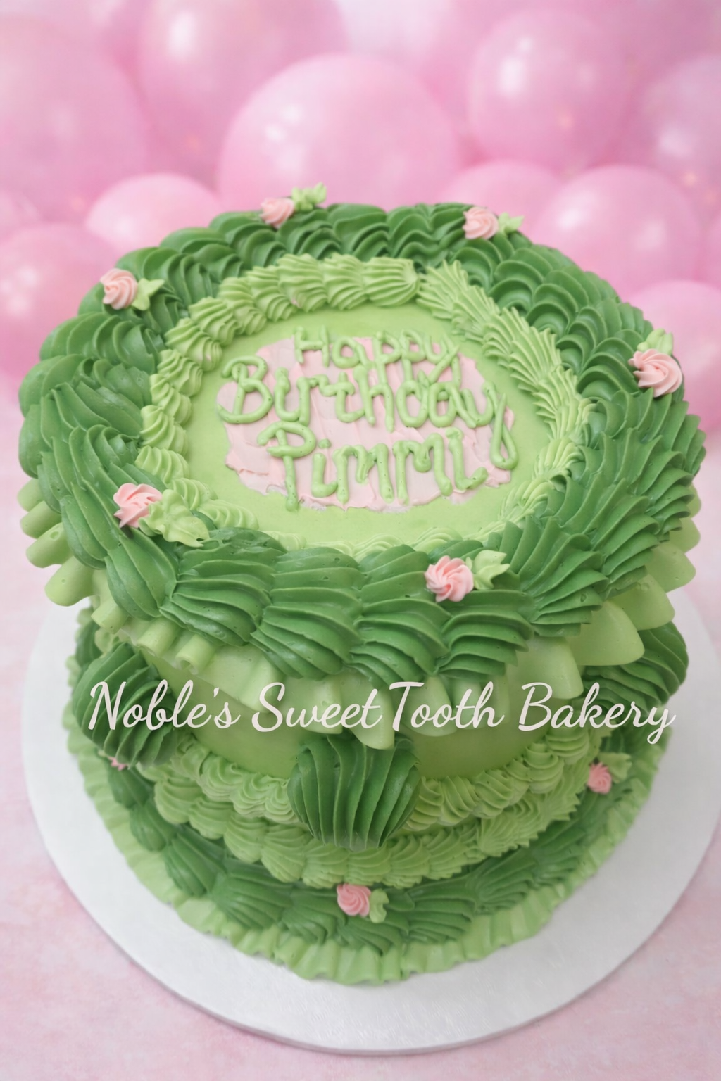 Green birthday cake with piped decorative frosting and pink flower accents, with a cake topper that says 'Happy Birthday, Liam.'