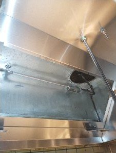 Close-up of a stainless steel kitchen sink with water running and a metal drain cover.