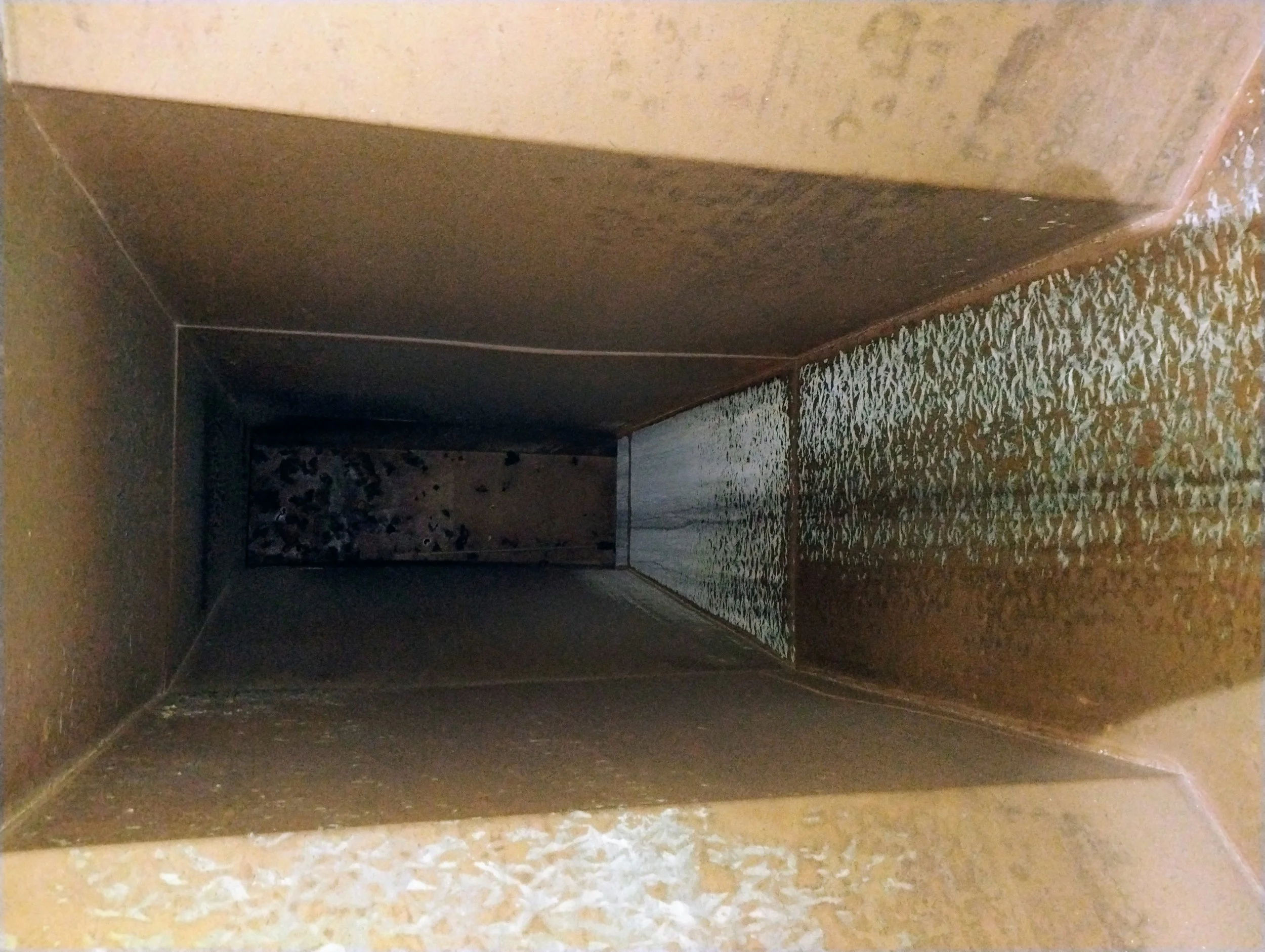 Inside view of a metal chimney or duct with some debris at the far end.