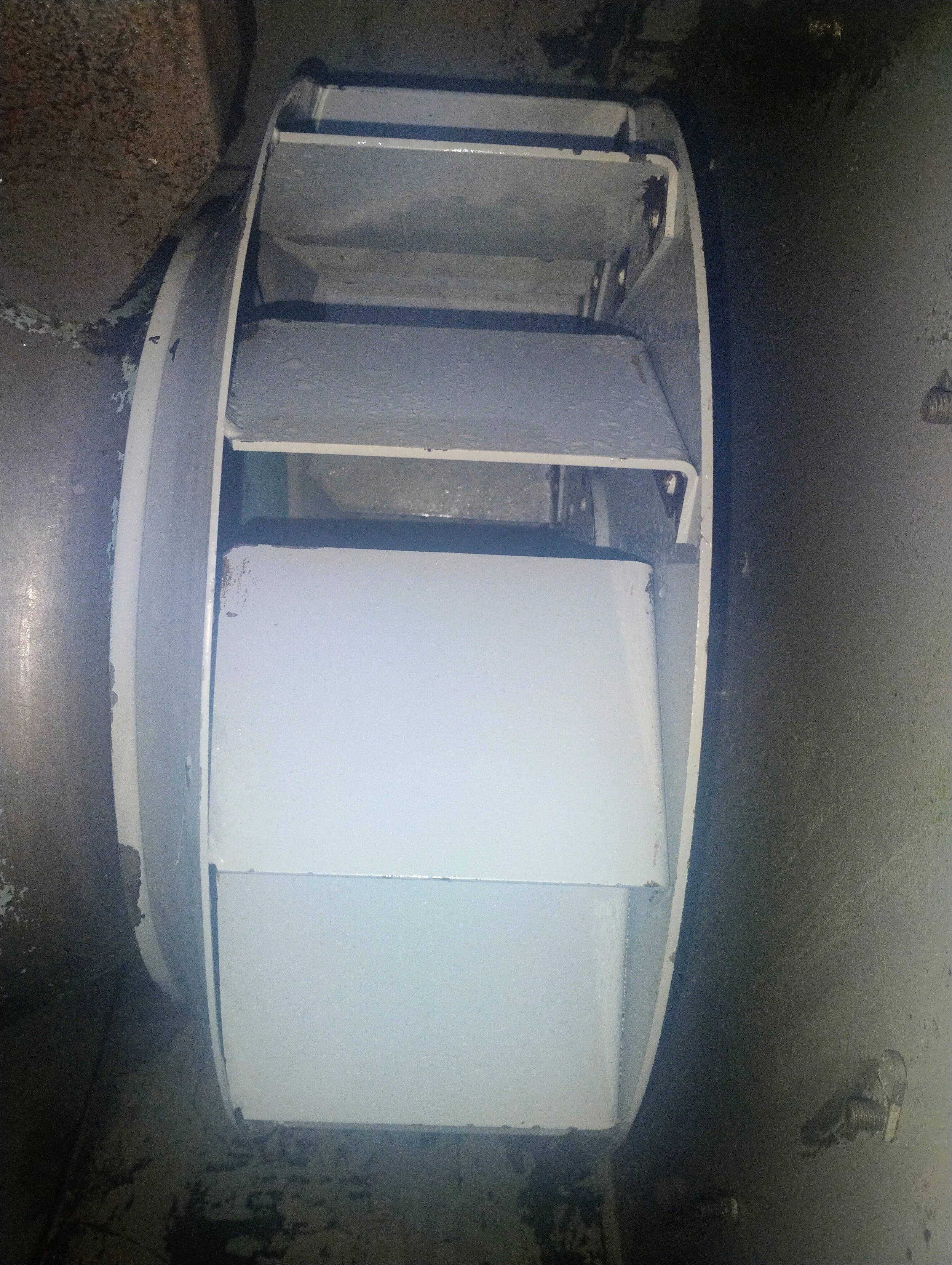 The image shows a metal boat hull with several wooden or metal panels inside, with some of the panels painted white.