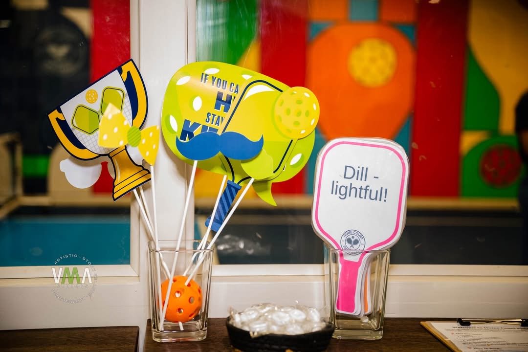 Decorative Mardi Gras-themed signs with bright colors and playful designs in glass containers on a table.