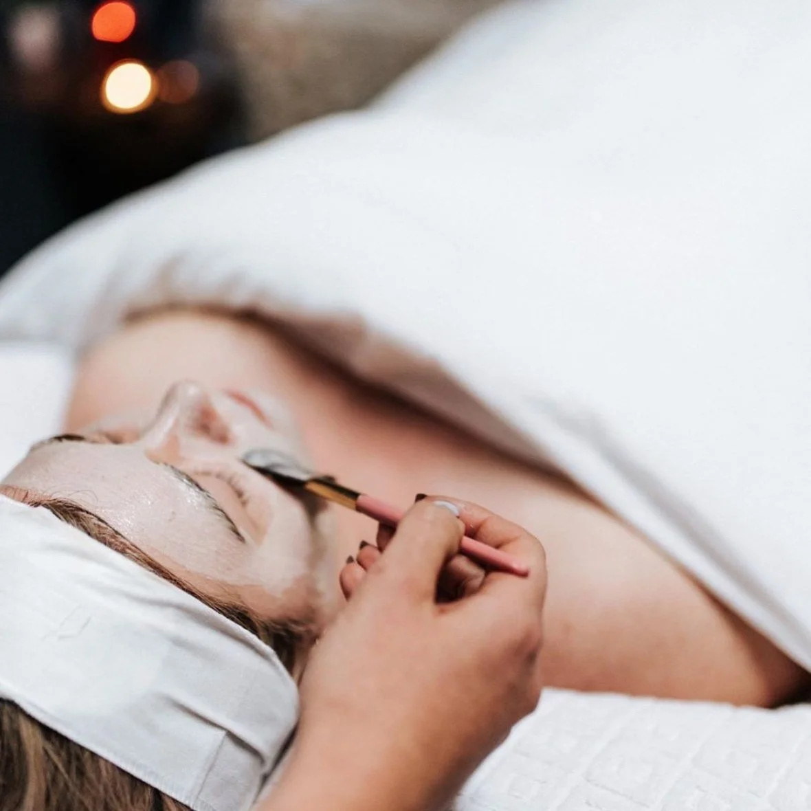 A young woman with blue eyes and light makeup looking at the camera, with overlayed hexagons showing close-up images of skin textures, indicating skincare or aging research.