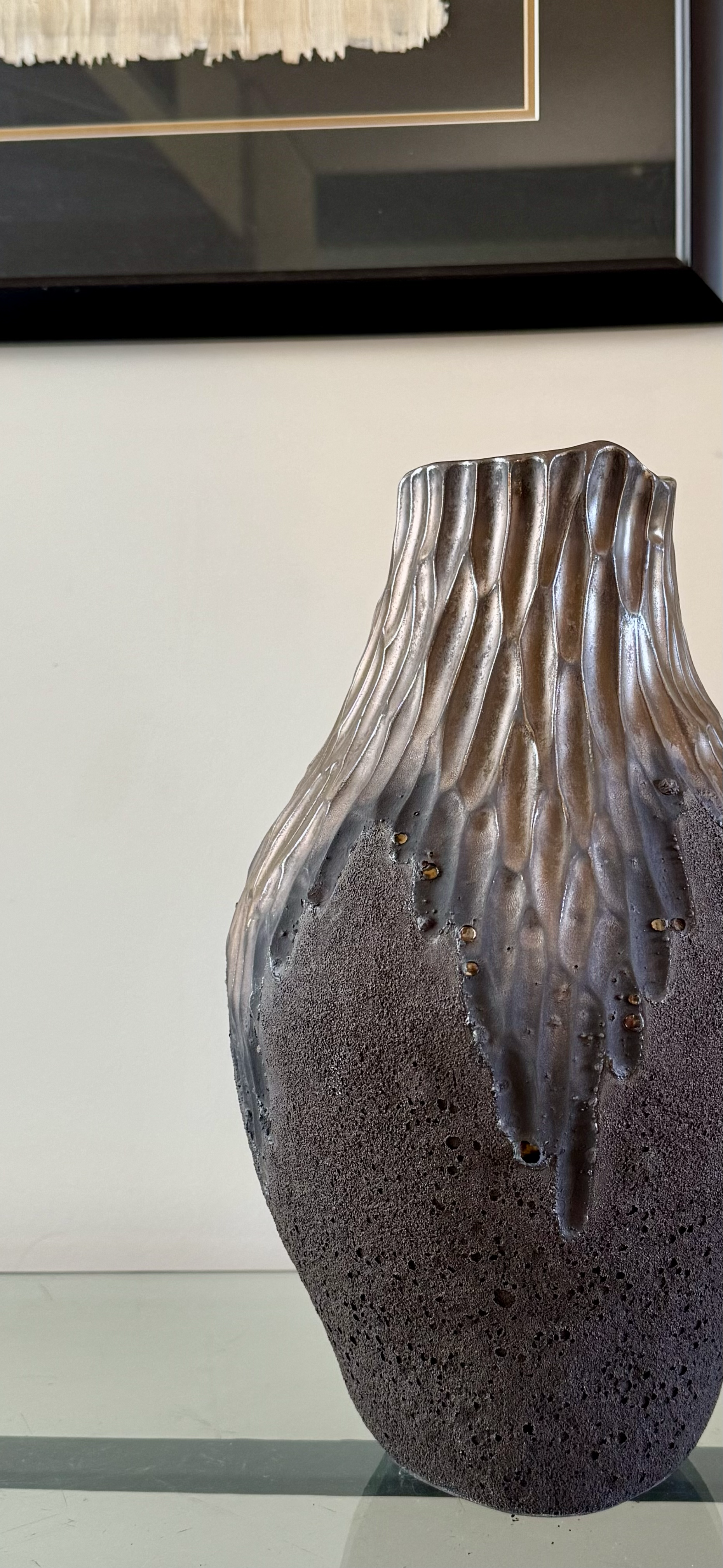 A ceramic vase with a textured, uneven surface and vertical ridges, featuring a color gradient from dark brown at the bottom to lighter, glossy brown towards the top.